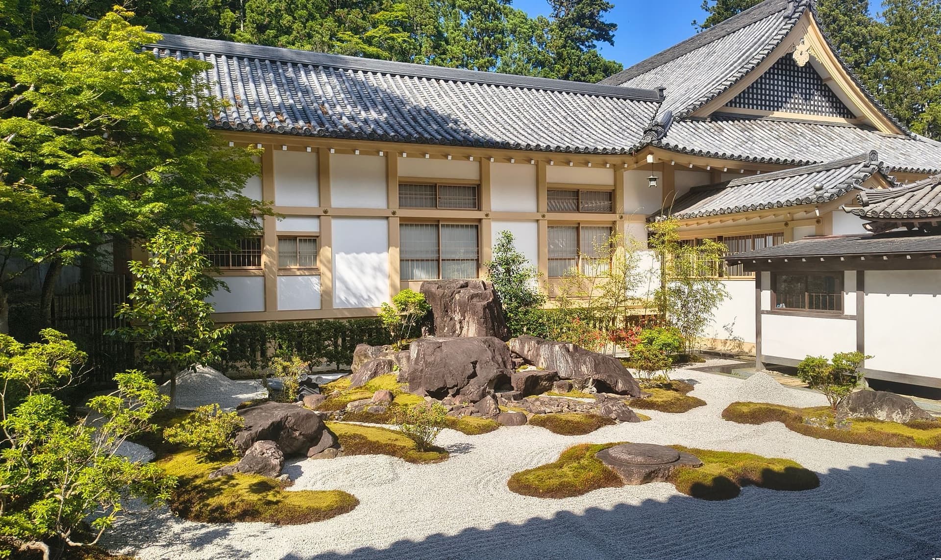 日本の枯山水。白砂に石を据え、奥に木造の建物。