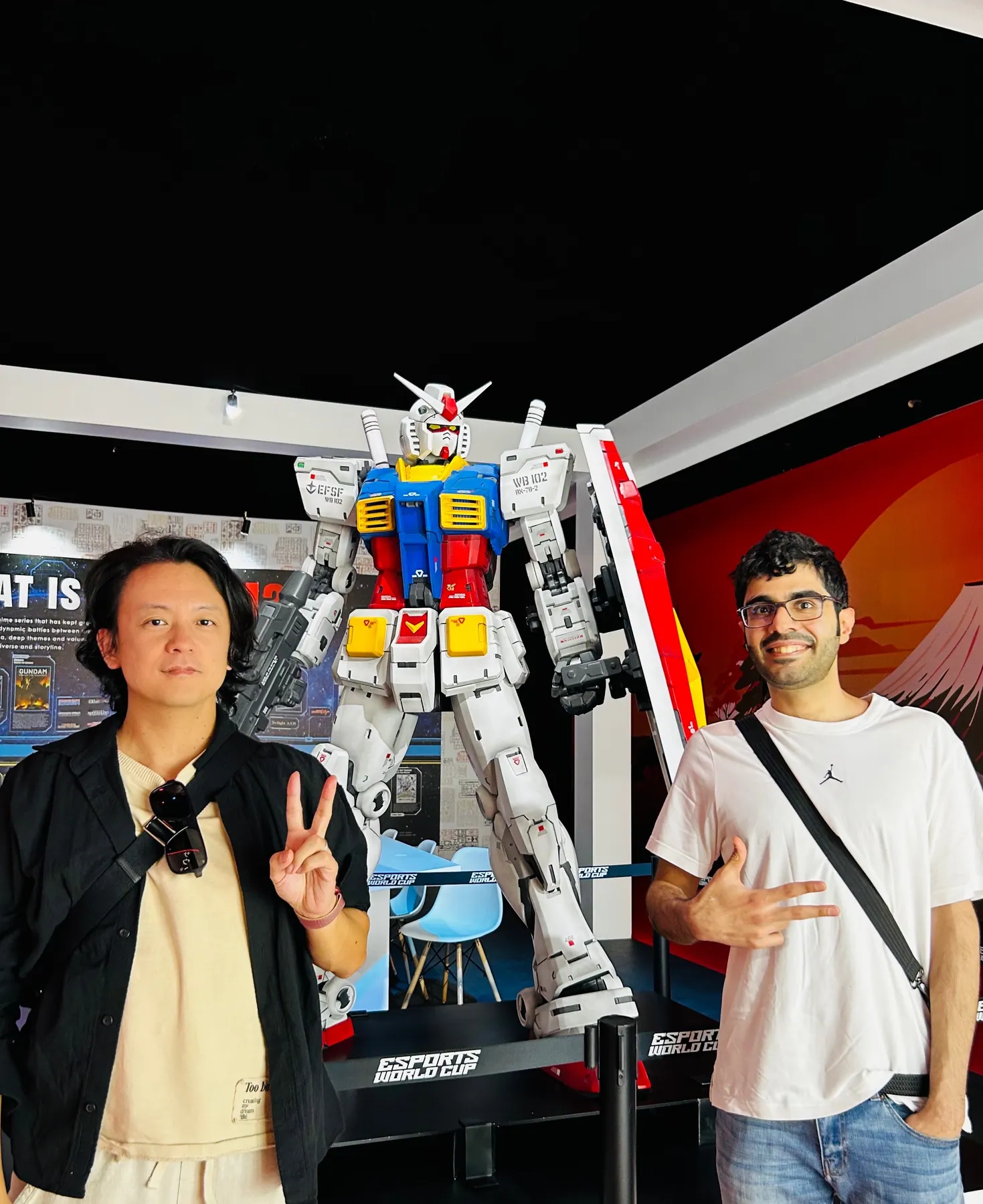 ガンダムの立像を前に並ぶ二人。日本のポップカルチャーに触れる一場面。