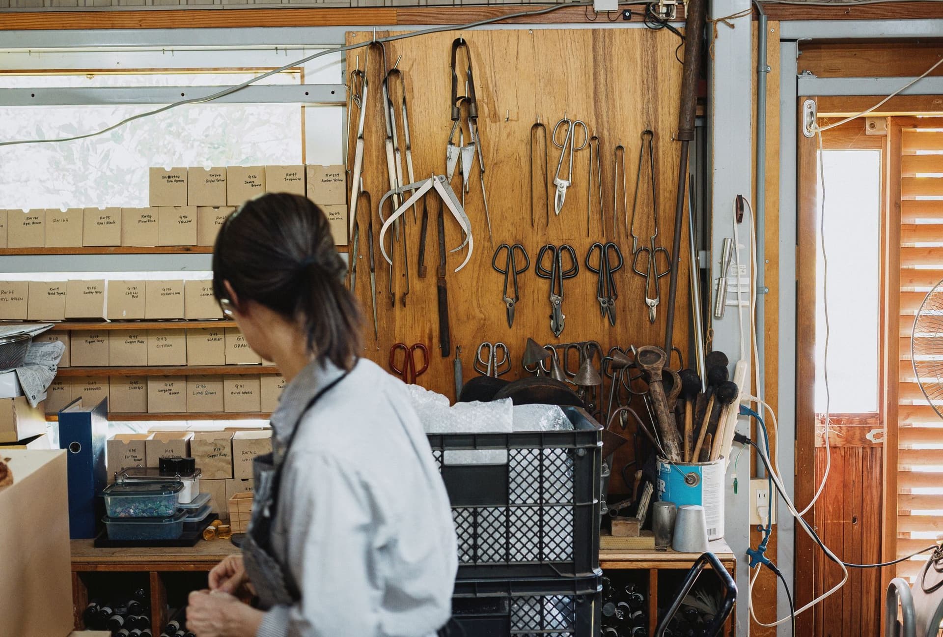 長野の工房。道具を掛けた壁の前で作業する職人。